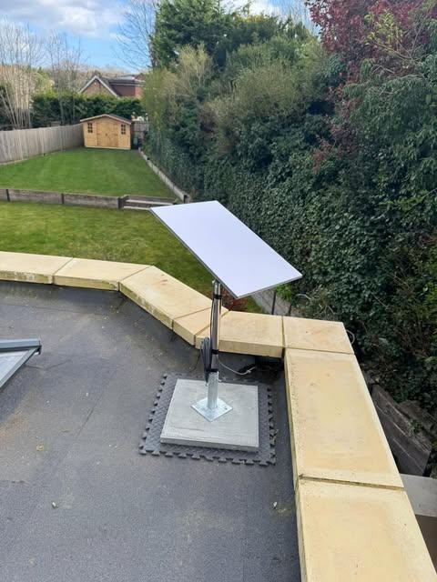Satellite dish on a flat roof with a concrete ballast mount and neat cable management