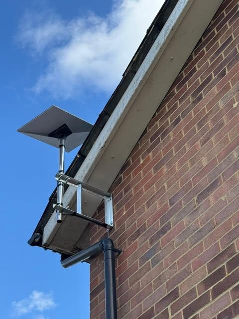 Satellite dish installed high on a brick house with a wall-mount bracket