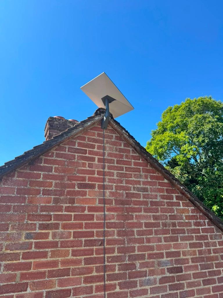 Professional satellite dish mount on a residential gable with tidy vertical cable routing