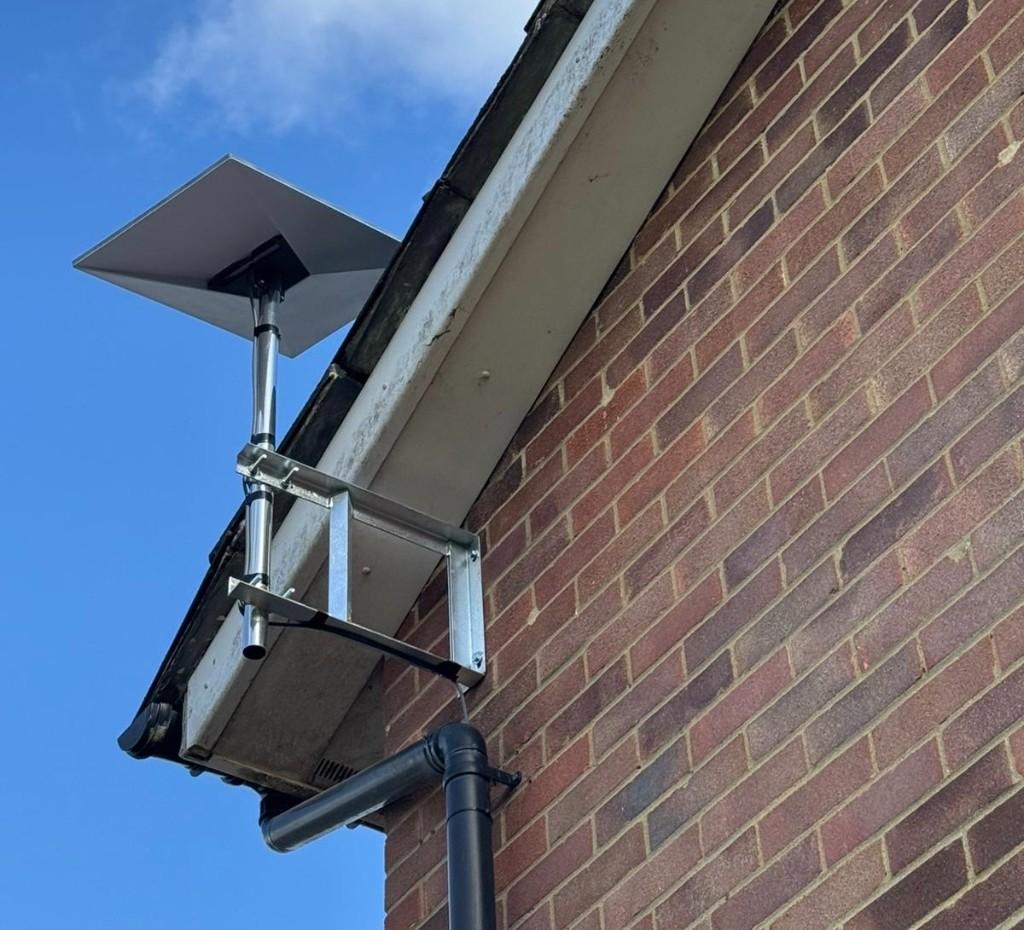 Starlink dish on an H bracket fascia mount clearing the roofline of a brick house
