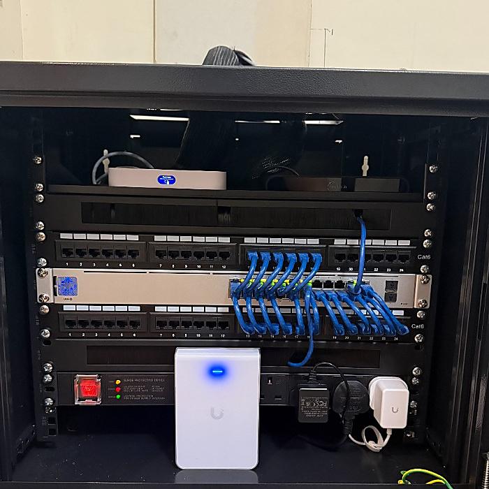 Neatly cabled UniFi home network rack with switch, patch panel and access point