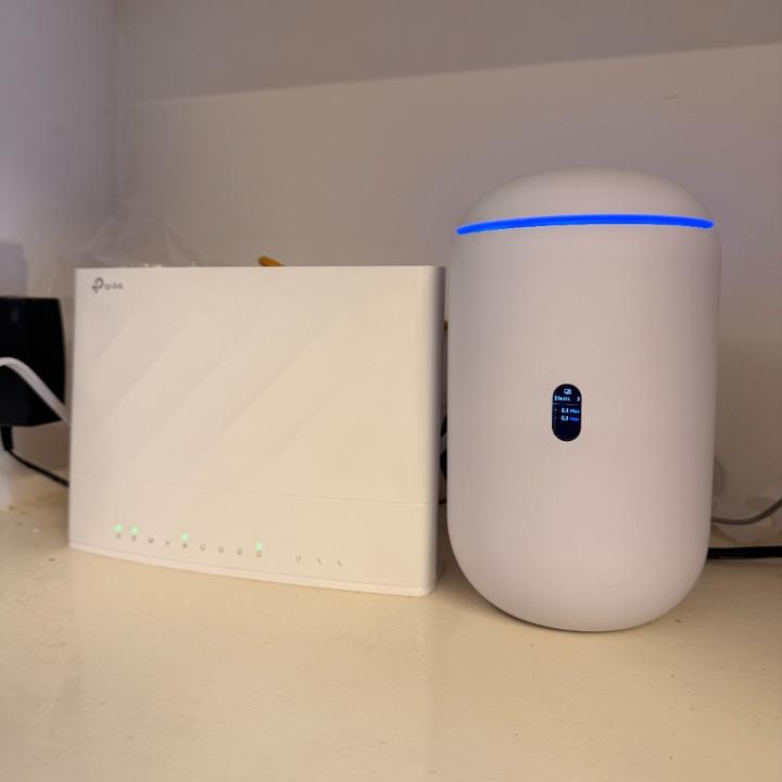Home gateway and UniFi Dream Router on a shelf with status lights on