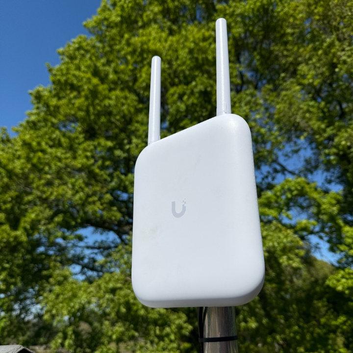 Outdoor UniFi mesh access point mounted on a pole for garden and outbuilding coverage