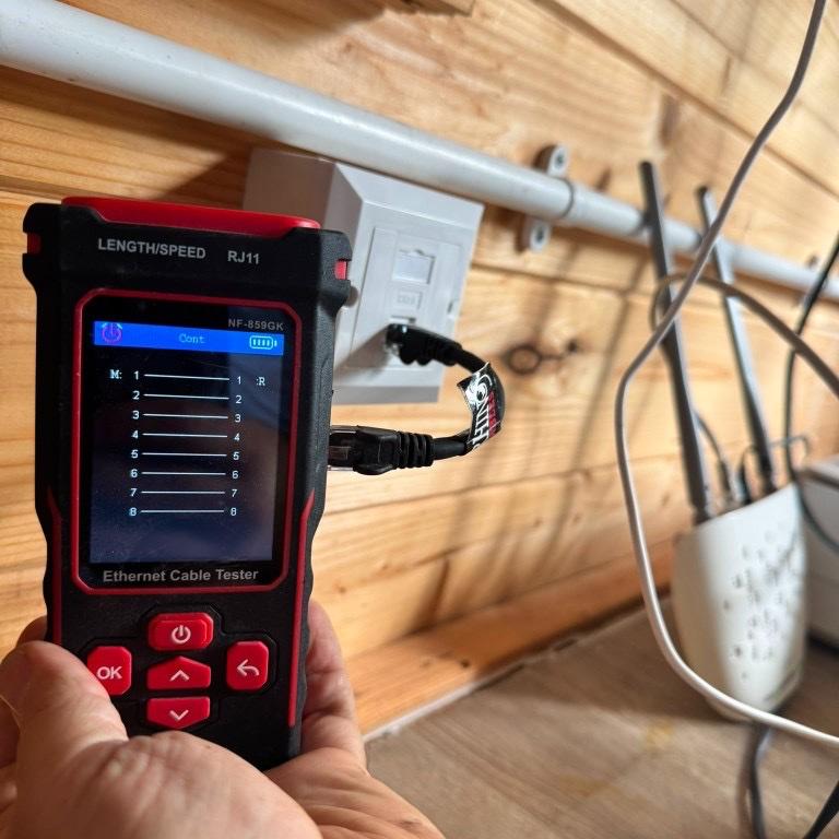 Ethernet cable tester confirming a successful continuity test on a newly installed Cat6 wall socket