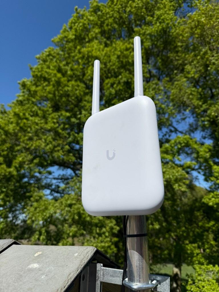 Outdoor UniFi mesh access point mounted on a pole for garden office and outbuilding WiFi coverage