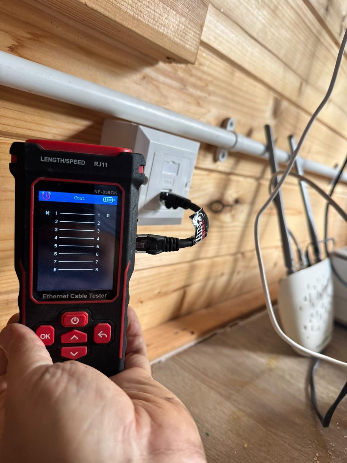 Engineer running an ethernet continuity test on a wall socket during a WiFi site survey visit